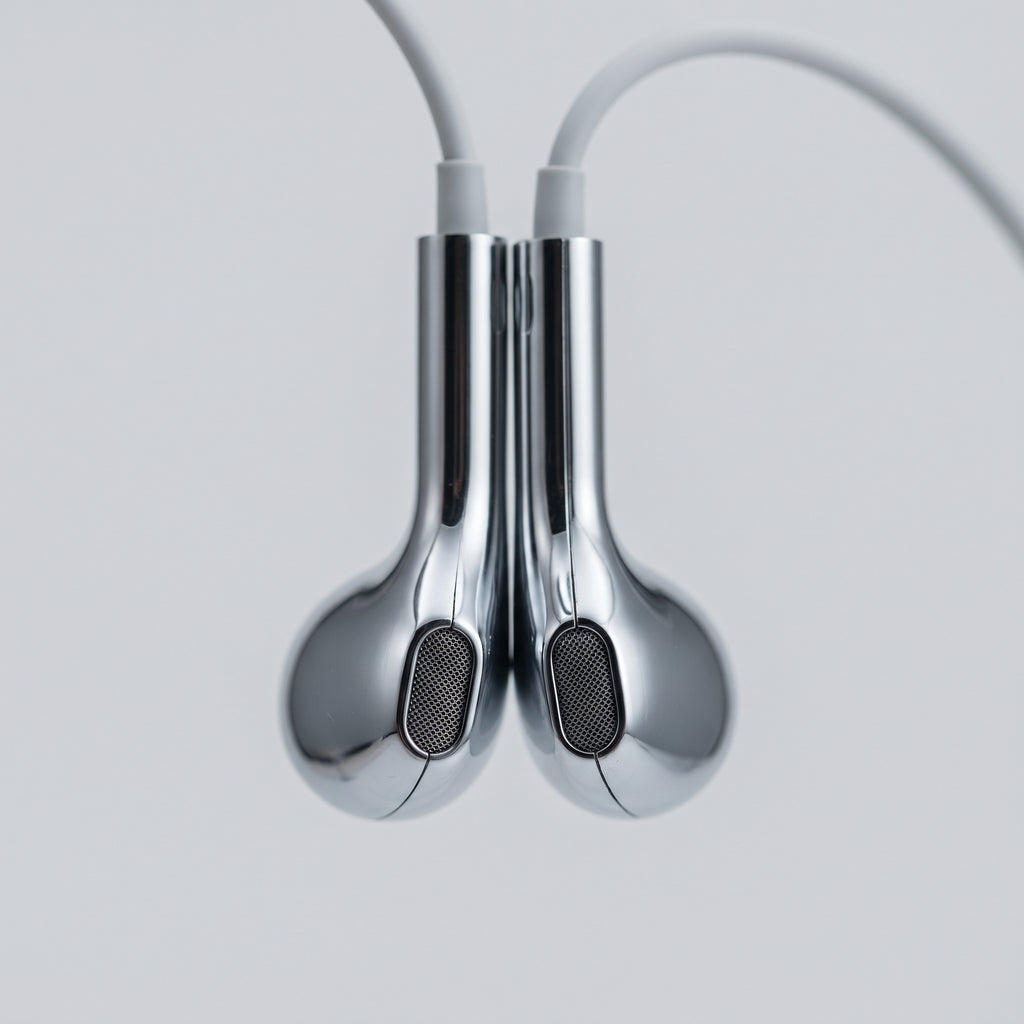 Close-up of the two mirror-chrome earbud housings and mesh grilles