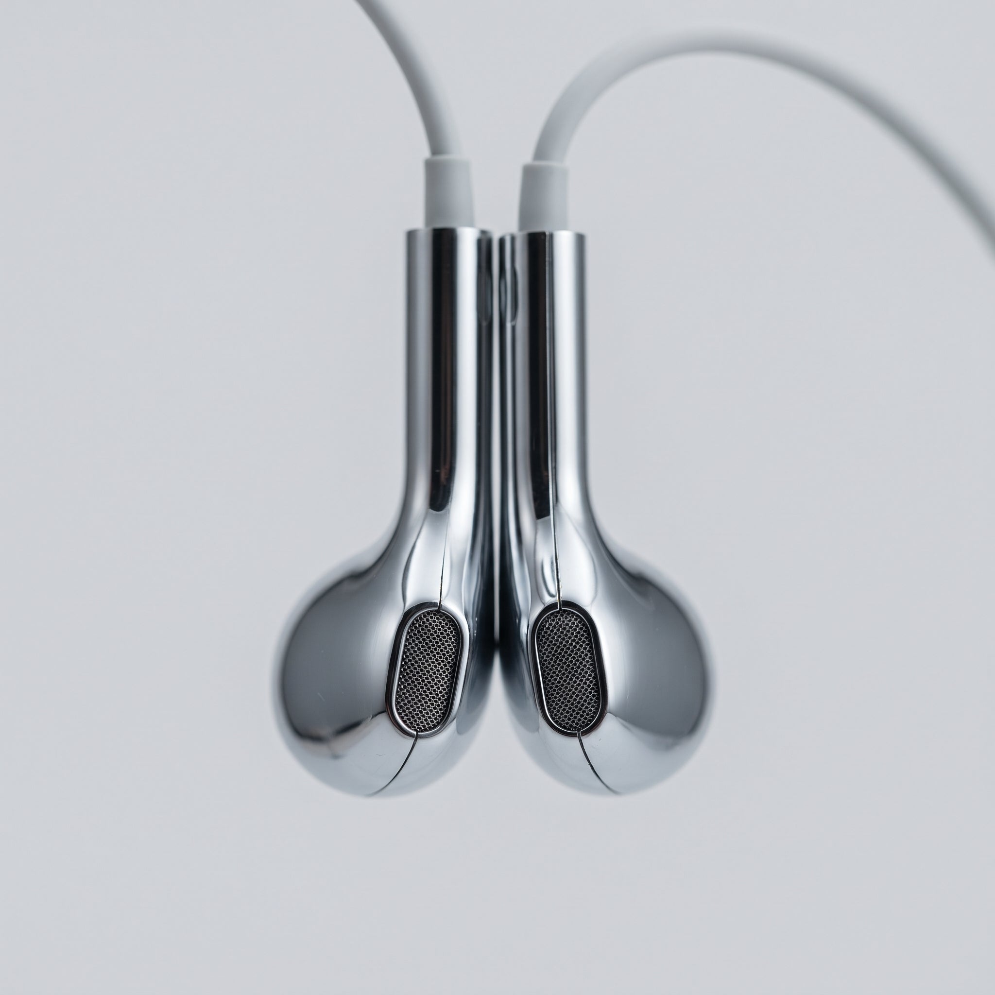 Close-up of the two mirror-chrome earbud housings and mesh grilles